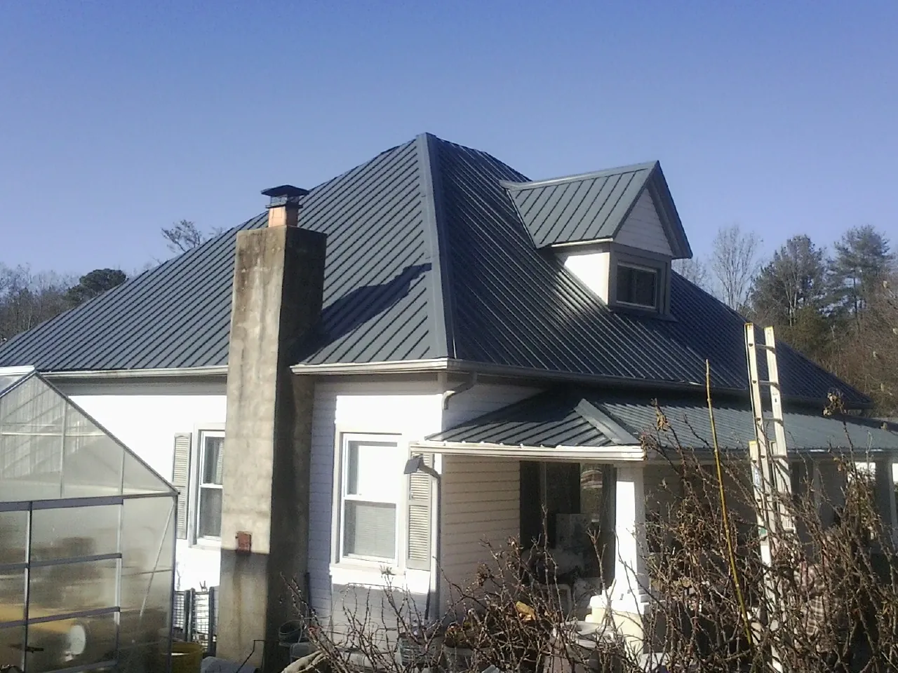 Dark blue standing seam metal roof on a white farmhouse with dormer — Slate & Tile Roof Repair by Roofing Brothers in Orford