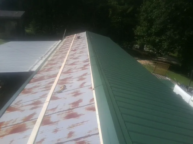 Old rusted panels beside newly installed green metal roofing — Wind Damage Roof Repair by Roofing Brothers in Orford