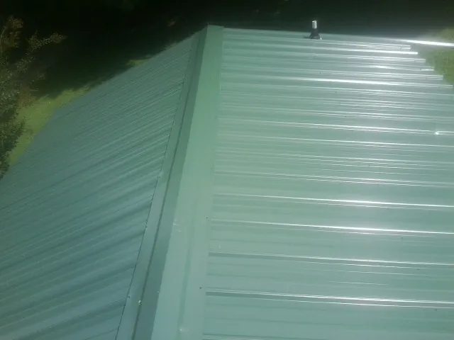 New green metal panels meeting at the ridge of a roof — Flat Roof Repair work by our crew in Orford