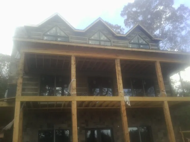 Dormers and porch framing on a large log home under construction — Roof Coating work by our crew in Orford