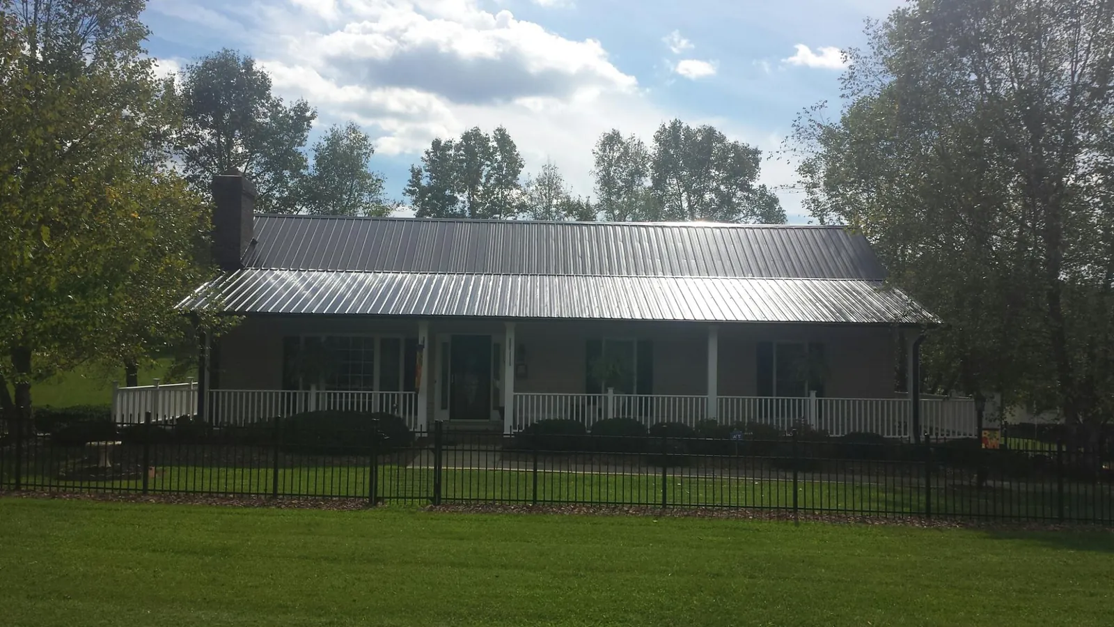 Gray metal roof on a brick ranch with a full width front porch — Gutter Guard Installation work by our crew in Orford