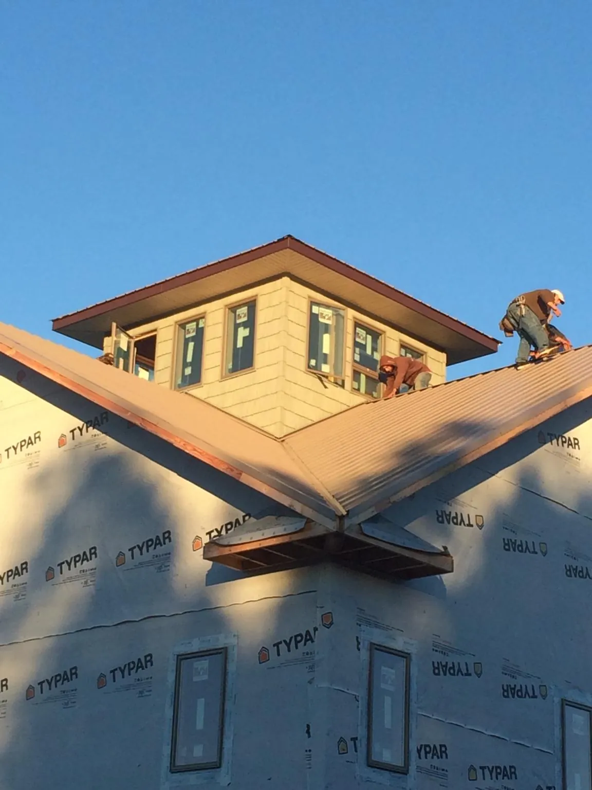 Roofers working around a rooftop cupola on a new metal roof at sunset — Roof Waterproofing in Orford by Roofing Brothers